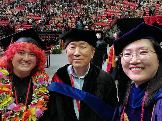student and two professors at commencmenet.