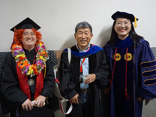 student and two faculty at commencement